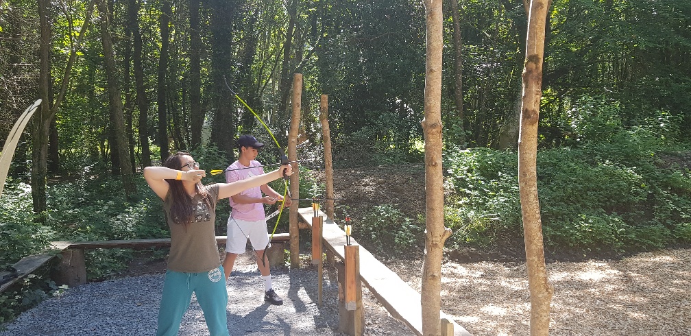 young girl and boy playing archery in the forest