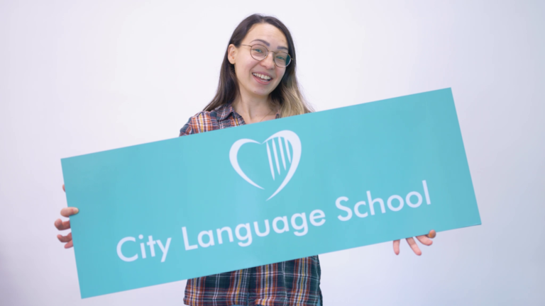 female student holding city language school sign