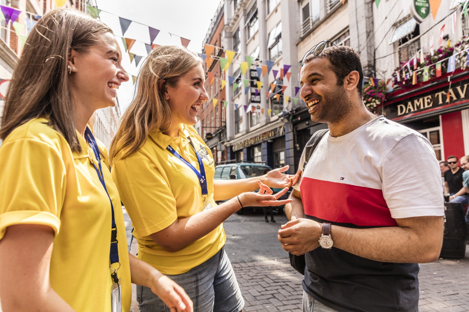 happy ces students in yellow t shirts talk to a friend on sunny dame street