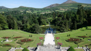The view from the Powerscourt Hotel, a pathway leading up to mountains and tall trees. 